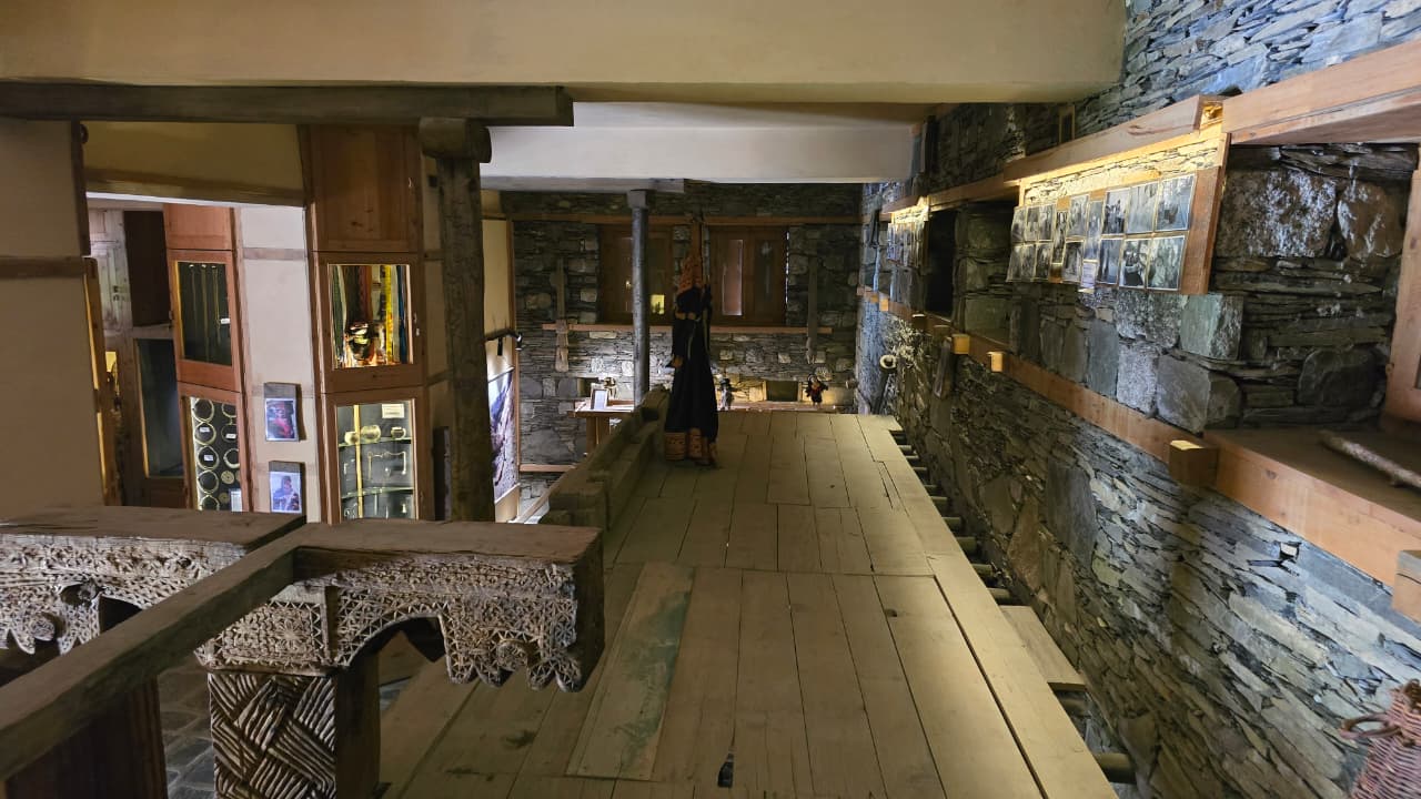 Interior corridor of the Kalasha Dur museum with wooden floors, stone walls and glass display cases