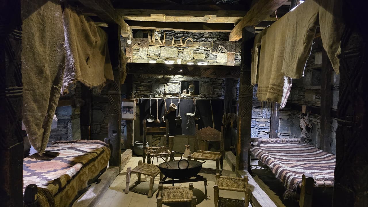 Reconstruction of a traditional Kalash living room with striped kilims, low seating and a central hearth